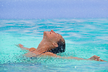 Image showing Rain, smile and swimming with woman in pool for travel, holiday or vacation as tourist. Relax, smile and water with happy young swimmer person outdoor at tropical resort for wellness or hospitality