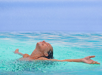 Image showing Face, freedom and rain with woman in swimming pool for travel, holiday or vacation as tourist. Relax, smile and wet in water with happy young swimmer person outdoor at tropical resort for getaway