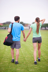 Image showing Couple, holding hands and back in park for workout, walking or training for wellness with bag in summer. People, man and woman for support, care or bonding on lawn for exercise for fitness in England