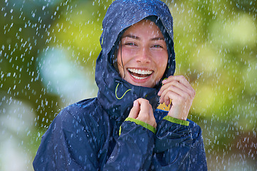 Image showing Woman, rain and portrait with laughing from winter climate, water and weather outdoor in a park. Happy, travel and female person with jacket for cold on holiday and vacation with raincoat and joy