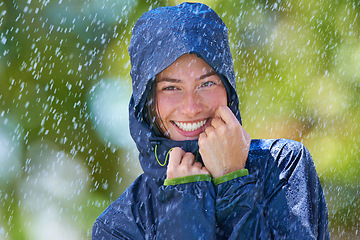 Image showing Woman, rain and portrait with a smile from winter climate, water and weather outdoor in a park. Happy, travel and female person with jacket for cold on holiday and vacation with raincoat and joy