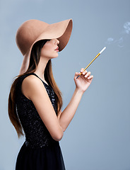 Image showing Glamour, profile and woman in hat with cigarette, confidence and vintage fashion in studio. Classic, chic and elegant style with girl smoking on grey background in designer clothes with aesthetic.