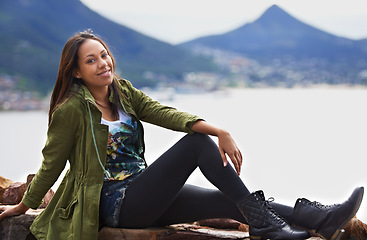 Image showing Portrait, woman and smile for sitting with mountain and sea on vacation, holiday or roadtrip. Female person, tourist or traveler with calm, joy and happiness while relaxing in Cape Town, South Africa