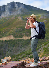 Image showing Man, traveler and binoculars with backpack for sightseeing, outdoor travel or hiking on mountain in nature Young male person, hiker or tourist with bag or optical instrument for view, vision or scope