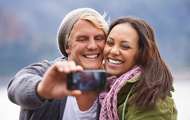 Image showing Selfie, phone screen and couple hug in nature for travel, freedom or road trip adventure together. Smartphone, photography and people with love outdoor for camping, journey or social media memory