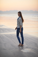 Image showing Woman, walking and happy in portrait at beach, sunset and vacation with nature to relax by ocean. Girl, person and outdoor by sea with feet in sand for holiday, adventure or smile by sea in Australia