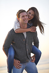 Image showing Portrait, piggy back and happy couple on beach at sunset for tropical holiday adventure, relax and bonding together. Love, man and woman on romantic date with ocean, evening sky and travel vacation.