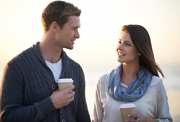 Image showing Couple, coffee and sunset by ocean on vacation, walking and conversation in summer at beach. Man, woman and drink with tea cup with smile, bonding and happy for memory on holiday by sea in Australia