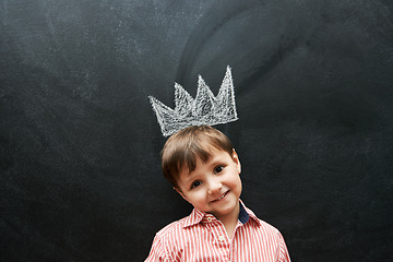 Image showing Little boy, portrait and crown on chalkboard in black background and smile for school in elementary class. Kid, happiness and education for development of learner, blackboard and cute drawing