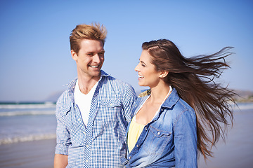 Image showing Couple, smile and walk on beach for romantic date on sunny afternoon with blue sky in New Zealand. Happy, man and woman in love for sweet relationship, fun dating and bonding together in summer