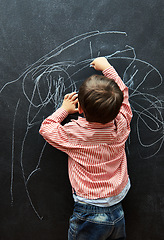 Image showing Young child, scribble and art on chalkboard in classroom of preschool for education of little boy. Kid, drawing and creative on blackboard with illustration for elementary, student and sketch