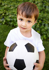 Image showing Portrait, young boy and hold with football in garden for fun game, exercise and fresh air in Peru. Closeup, innocent and male kid with soccer ball for outdoor activity and childhood development