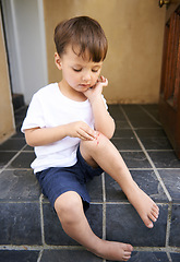 Image showing Small child, injured and bleed on knee from fall, scratch and youth in pain from bruise on leg. Young boy, sitting and stairs outdoor house, looking and wound on skin from accident, touch and hand