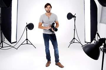 Image showing Photographer, portrait or lighting with camera in studio for career, behind the scenes or confidence. Photography, guy and equipment with electronics, flash or shooting gear for photoshoot or passion