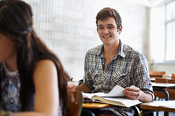 Image showing Happy, man and studying in textbook for information, reading and knowledge for assignment in university. Student, scholarship or positive in college by desk, journal or academic research for learning