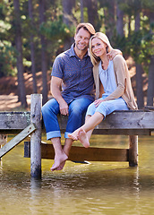 Image showing Mature couple, portrait and lake of countryside and together for love in marriage. Happiness, smile and hug by partner, family and woman with man sitting on dock for sightseeing and relax in nature