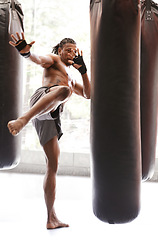 Image showing Man, kick boxing and bag with training, foot and combat for exercise with balance, power and precision in gym. African athlete, person or fighter with workout, fitness or strike for challenge in dojo