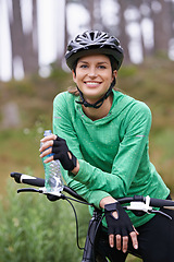 Image showing Happy woman, portrait and cyclist with water bottle on bicycle for cycling, fitness or break in nature. Thirsty female person, athlete or biker with drink or smile in forest, rest or outdoor workout