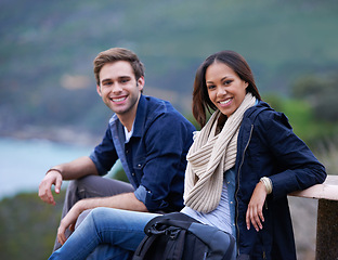 Image showing Couple, relax and portrait in nature for outdoor date and adventure in winter on valentines day. Excited, interracial people with backpack on bench for hiking, trekking or travel break on mountains