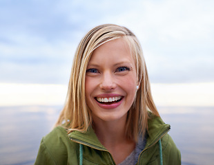 Image showing Woman, excited and smile at the beach for holiday, vacation and travel in winter portrait. Face of a young person from the USA and happy by an ocean, sea or lake with cloudy sky for outdoor adventure