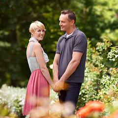 Image showing Holding hands, love and couple in a park with care, support and trust while bonding outdoor. Security, travel and people standing in a field of flowers for holiday, vacation or romantic summer date