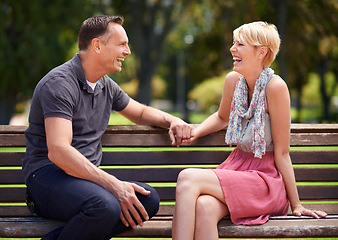 Image showing Love, laughing and happy couple on a park bench with funny conversation, gossip or bonding outdoors together. Trust, communication or people sharing comic, chat or speaking on travel, trip or holiday