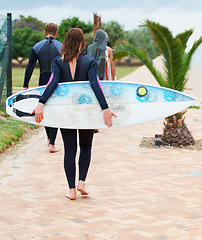 Image showing Surfer, rear view and friends or walking outdoor with surfboard for adventure, vacation and holiday. Surfing, group and people with travel in nature for exercise, water sports and swimming in summer