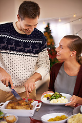 Image showing Christmas, happy couple and eating dinner in home, smile or bonding together at party. Xmas, man or woman at table for food at festive celebration, relax or people on holiday cutting chicken for meal