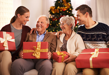 Image showing People, grandparents and family with Christmas gift for festive season together for celebration, presents or holiday. Elderly man, woman and couch at home in Canada for bonding, vacation or relaxing