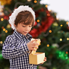 Image showing Happy, Christmas and boy child with gift for celebration or surprise at festive party at home. Smile, santa hat and cute young kid opening a present box for xmas event at modern house with decoration