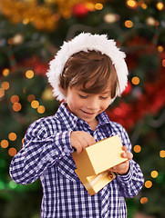 Image showing Happy, Christmas and boy child with present for celebration or surprise at festive party at home. Smile, santa hat and cute young kid opening a gift box for xmas event at modern house with decoration