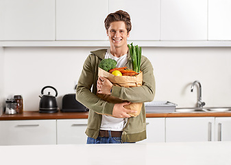 Image showing Portrait, vegetables and man with brown paper bag, home and wellness with nutrition and vegetarian. Face, person and guy with groceries and healthy ingredients with products, food and diet in kitchen