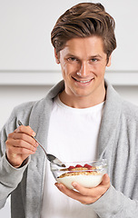 Image showing Smile, portrait and man with cereal in kitchen of home for hydration, health and wellness. Happy, confident and young male person eating breakfast with fruit, yoghurt and muesli in modern apartment.