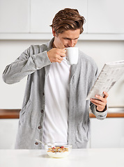Image showing Coffee, breakfast and man with newspaper in kitchen for information at modern apartment. Nutrition, cereal and young male person drinking cappuccino or latte and reading journalism article at home.
