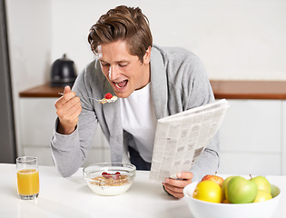 Image showing Cereal, juice and man with newspaper in kitchen for information at modern apartment. Nutrition, breakfast and young male person drinking healthy beverage and reading journalism article at home.