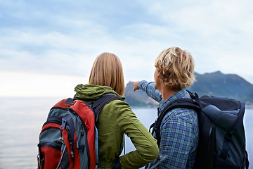 Image showing Hiking, nature and couple on mountain pointing with backpack for freedom, trekking or explore landscape. Travel, dating and man and woman hug by scenic view on holiday, vacation and outdoor adventure