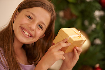 Image showing Christmas, tree and portrait of child with gift box, smile and celebration with happy surprise package in home. Holiday, festive and girl with present, xmas gratitude and excited fun in apartment