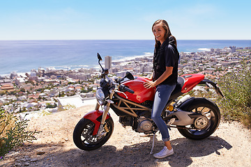 Image showing Happy woman, biker and motorcycle in city by the ocean coast for road trip, travel or outdoor holiday in nature. Female person or rider with smile, bike or transport on cliff or ledge in neighborhood