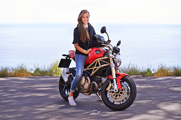 Image showing Happy woman, portrait and biker on motorcycle by the ocean coast for road trip, travel or outdoor holiday in nature. Extreme female person with smile on ride for transport or sightseeing by the beach
