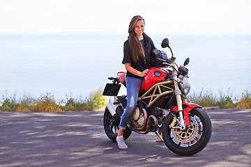 Image showing Happy woman, portrait and rider on motorcycle by the ocean coast for road trip, travel or outdoor holiday in nature. Extreme female person with smile on ride for transport or sightseeing by the beach