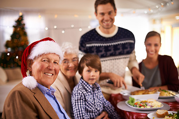 Image showing Family, portrait and grandparents at dinner on Christmas, together with food and celebration in home. Happy, event and kid smile with grandmother at lunch and relax at holiday, party or hosting meal