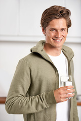 Image showing Smile, portrait and man with glass of water in kitchen of home for hydration, health and wellness. Happy, confident and young male person drinking fresh h2o liquid or beverage in modern apartment.