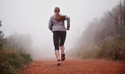 Image showing Woman, rear view and running in woods with fitness for exercise, morning routine and workout with fog and legs. Athlete, person and cardio with sportswear on outdoor trail and forest for wellness
