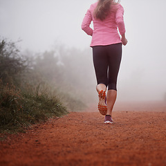 Image showing Woman, rear view and running in forest with fitness for exercise, morning routine and workout with fog and legs. Athlete, person and cardio with sportswear on mountain trail and woods for wellness