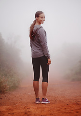 Image showing Woman, portrait and hiking in forest with fog for exercise, morning routine and workout with fitness and smile. Athlete, face and person with happiness on mountain trail for wellness and healthy body