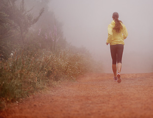 Image showing Woman, rear view and running in woods with exercise for fitness, morning routine and workout with fog and legs. Athlete, person and cardio with sportswear on outdoor trail and forest for wellness