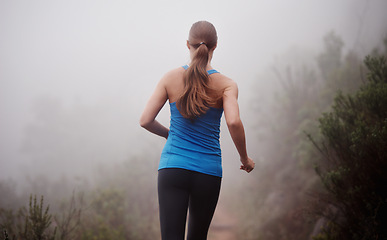 Image showing Woman, rear view and running in woods with workout for exercise, morning routine and fitness with fog and mist. Athlete, person and cardio with sportswear on outdoor trail and forest for wellness