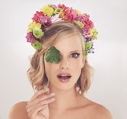 Image showing Woman, portrait and surprised with flowers on crown in studio with makeup and leaf for cosmetics and skincare. Spring aesthetic, model and face or shocked with floral headband on white background