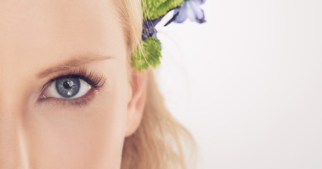 Image showing Woman, flowers and half face in studio with beauty, makeup or cosmetics with eyelash extensions on mockup space. Model, person and portrait with collagen, skincare or glowing skin on white background