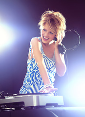 Image showing Woman, dj and record player with headphones for music on stage with lens flare, mixing and gig at rave party for entertainment. Female sound mixer, artist and musician with turntable or playlist